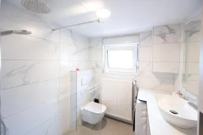 a white bathroom with a toilet and a sink at The Nice Apartment in Domžale