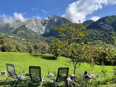 three chairs in a field with mountains in the background at Holiday home Dreams in Kobarid
