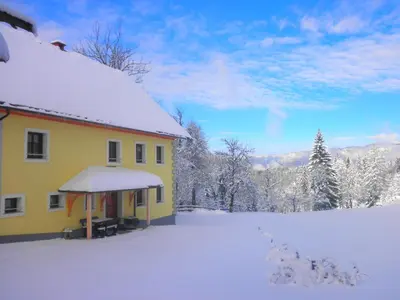 a yellow house with snow on the ground at Apartments Čumar in Cerkno
