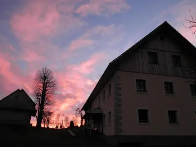 a barn with a sunset in the background at Apartments Čumar in Cerkno