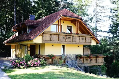 a small yellow house with a balcony and flowers at Country House Apat in Šoštanj