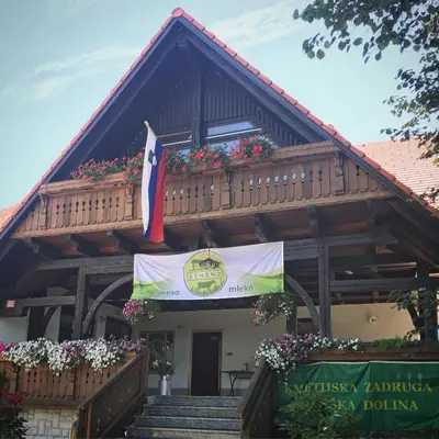a building with a flag and a balcony with flowers at Country House Apat in Šoštanj