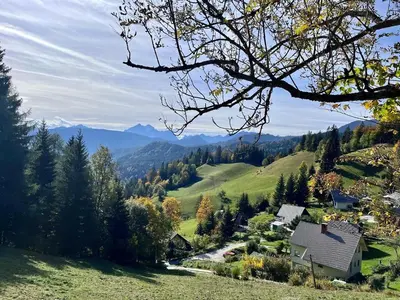 a house on a hill with mountains in the background at Apartments Pri Fencu in Jesenice