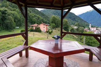 a wooden table with a vase of flowers on a porch at Apartma pr' Gamilcu in Tolmin