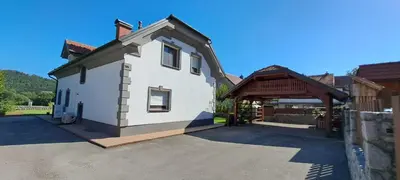 a white house with a gate and a building at Hisa Haasberg in Planina