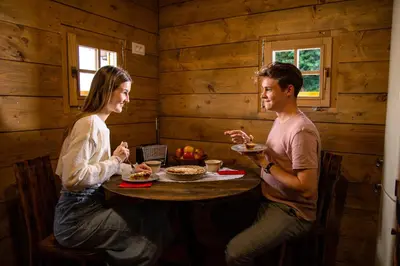 a man and a woman sitting at a table eating food at Glamping Paradise Škatlar in Otočec