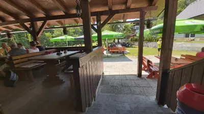 a group of people sitting at a table under a pavilion at Hostel in picerija Špajza in Mojstrana