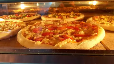 a group of pizzas in a display case at Hostel in picerija Špajza in Mojstrana