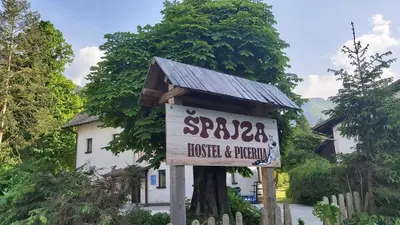 a sign in front of a house and a building at Hostel in picerija Špajza in Mojstrana
