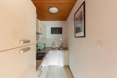 a kitchen with white cabinets and a wooden ceiling at Apartma Alpine Space, Kranjska Gora - Center in Kranjska Gora