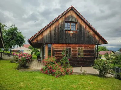 a log cabin with flowers in front of it at Old Taylor's house in Gradac