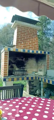 a brick fireplace with a table and a bench at Fairytale Wooden house by Ljubljana in Grosuplje