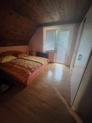a bedroom with a bed and a wooden floor at Rooms MARETČ in Bohinj