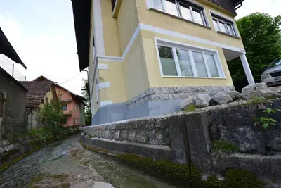 a house on a stone wall next to a river at Apartments Mojca in Bled