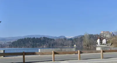 a road with a fence next to a body of water at Apartments Mojca in Bled