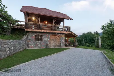 a log cabin with a stone wall and a driveway at Zidan'ca Rošel in Dolenjske Toplice