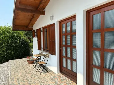 a house with wooden doors and chairs on a patio at Studio Apartma Olive, Nova Gorica, Slovenia in Nova Gorica