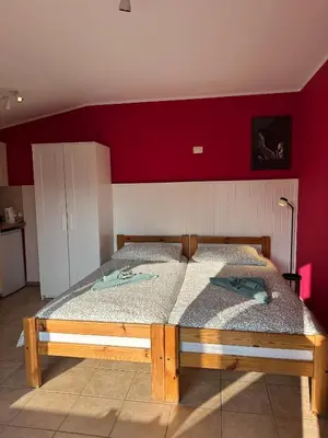 a bedroom with a wooden bed with a red wall at Studio Apartma Olive, Nova Gorica, Slovenia in Nova Gorica