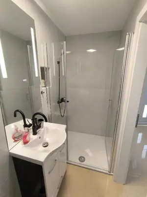 a white bathroom with a shower and a sink at JO-MA apartma - FREE parking in Ljubljana