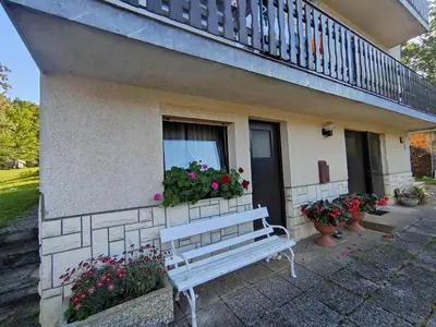 a white bench in front of a house with flowers at Homestay Zajec in Grosuplje
