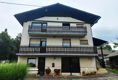 a white house with a balcony on top of it at Homestay Zajec in Grosuplje