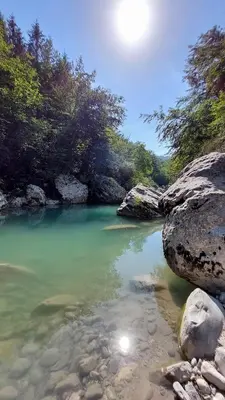 a body of water with some rocks and trees at Apartma Bella Nadiža in Kobarid