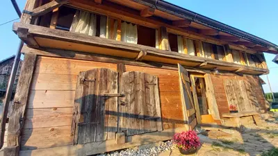an old wooden building with a door and flowers at Pig barn - Svinjaki in Krasinec