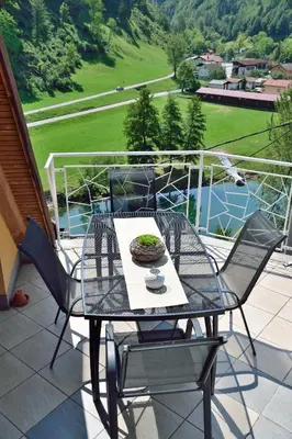 a table and four chairs on a balcony with a view at Apartment Sotočje in Dolenja Trebuša