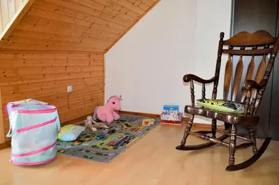 a room with a rocking chair and a rug at Apartment Sotočje in Dolenja Trebuša