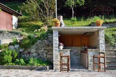 a stone shelter with two chairs and a table at Apartment Sotočje in Dolenja Trebuša