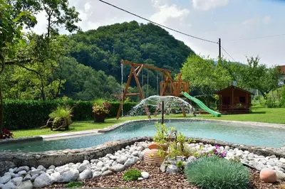 a swimming pool in a yard with a playground at Apartment Sotočje in Dolenja Trebuša