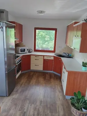 a kitchen with wooden cabinets and a large window at Apartma Julia in Spodnje Gorje