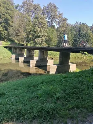 a man riding a bike on a bridge over a river at Na vrtu K25 in Gradac