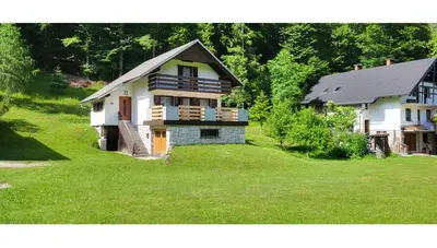 a house on a grassy yard next to a house at Počitniška hiša pr Puc in Mojstrana