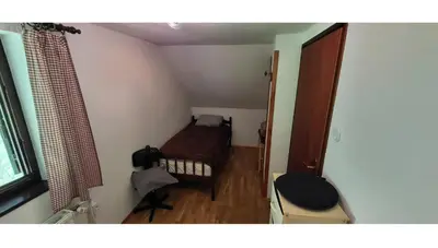 a small bedroom with a bed and a chair at Počitniška hiša pr Puc in Mojstrana