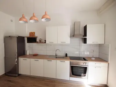 a kitchen with white cabinets and a stainless steel refrigerator at In the Center of Rogaška Slatina! Apartment Fani and Studio Marija in Rogaška Slatina