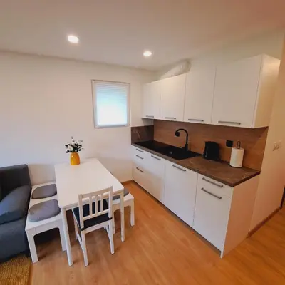 a kitchen with white cabinets and a table and a couch at BovecEnter Apartments Kaninska vas in Bovec