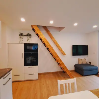 a living room with a staircase and a couch at BovecEnter Apartments Kaninska vas in Bovec