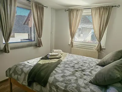 a bedroom with a bed and two windows at Apartma Bela in Bohinjska Bela