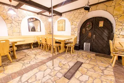 a restaurant with wooden tables and chairs and a stone wall at Holiday Home Juričko with private Sauna in Bizeljsko