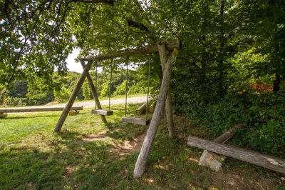 a swing set in a field with a tree at Holiday Home Juričko with private Sauna in Bizeljsko