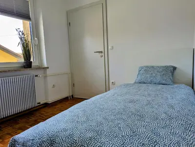 a bedroom with a bed with a blue comforter and a window at Domen's cozy rentals in Kranj