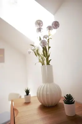a white vase with flowers in it on a table at Domen's cozy rentals in Kranj