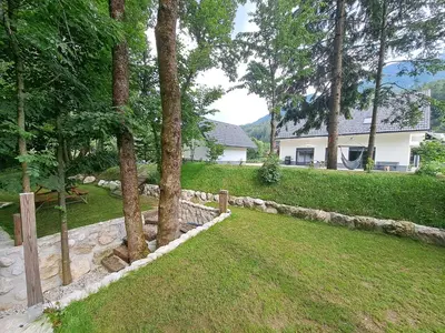 a yard with a bench and trees and a house at Riverside Apartma 1, Kranjska Gora in Kranjska Gora