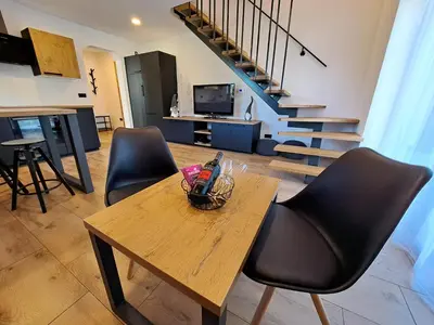 a living room with a table and chairs and a staircase at Riverside Apartma 1, Kranjska Gora in Kranjska Gora