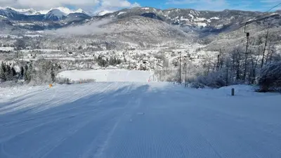 a road covered in snow with mountains in the background at Nad tunelom apartment Bohinj in Bohinj