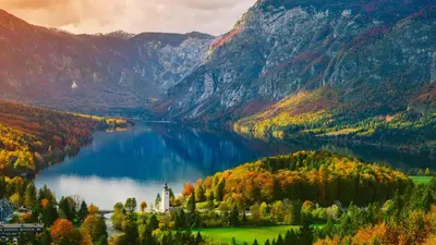 a lake with a castle in the middle of a mountain at Nad tunelom apartment Bohinj in Bohinj