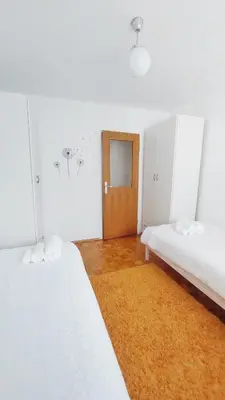 a room with two white beds and a door at Harmony House Velenje in Velenje