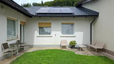 a patio with chairs and a table and a lawn at Harmony House Velenje in Velenje