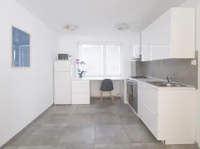 a kitchen with white cabinets and a sink and a chair at Harmony House Velenje in Velenje